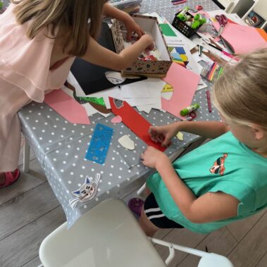 Na stole leżą materiały i dziewczynki przy pracy