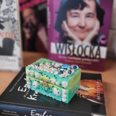 Szkatułka z przyklejonymi muszelkami w okolicy książek