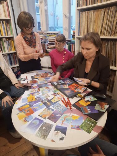 Agnieszka Zientarska rozdaje kartki tematyczne i kładąc na stoliku