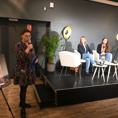 Konferansjerka wita gości, na scenie uczestniczki panelu