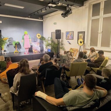Widok na salę na scenie trwa przedstawienie clownki Cioci Krysi, oglądają dzieci i rodzice