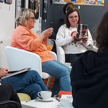 Czytelnicy słuchają co mówi jedna z czytelniczek i prezentuje książkę