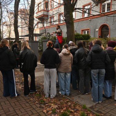 Uczestnicy na ulicy Konarskiego przed domem, Jakub Kornhauser czyta książkę