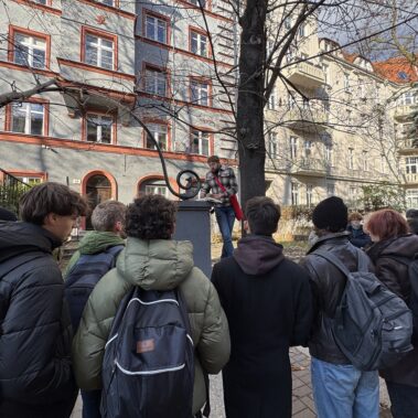 Uczestnicy na ulicy Konarskiego przed domem, Jakub Kornhauser czyta książkę