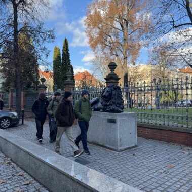 Uczestnicy na ulicy Dolnych Wałów przed Muzeum Caro i przechodzą koło rzeźby lwa