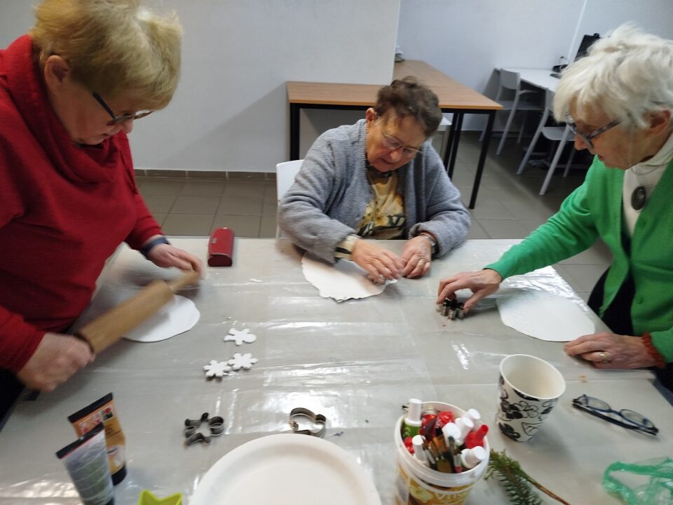 Seniorki przygotowują zawieszki z masy samoutwardzalnej - wałkują i wycinają za pomocą formy do ciast