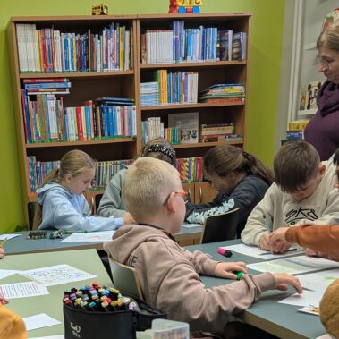 Dzieci rozwiązują zadania pod okiem nauczycielki
