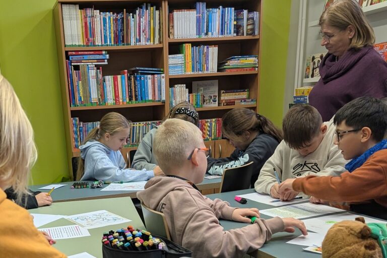 Dzieci rozwiązują zadania pod okiem nauczycielki