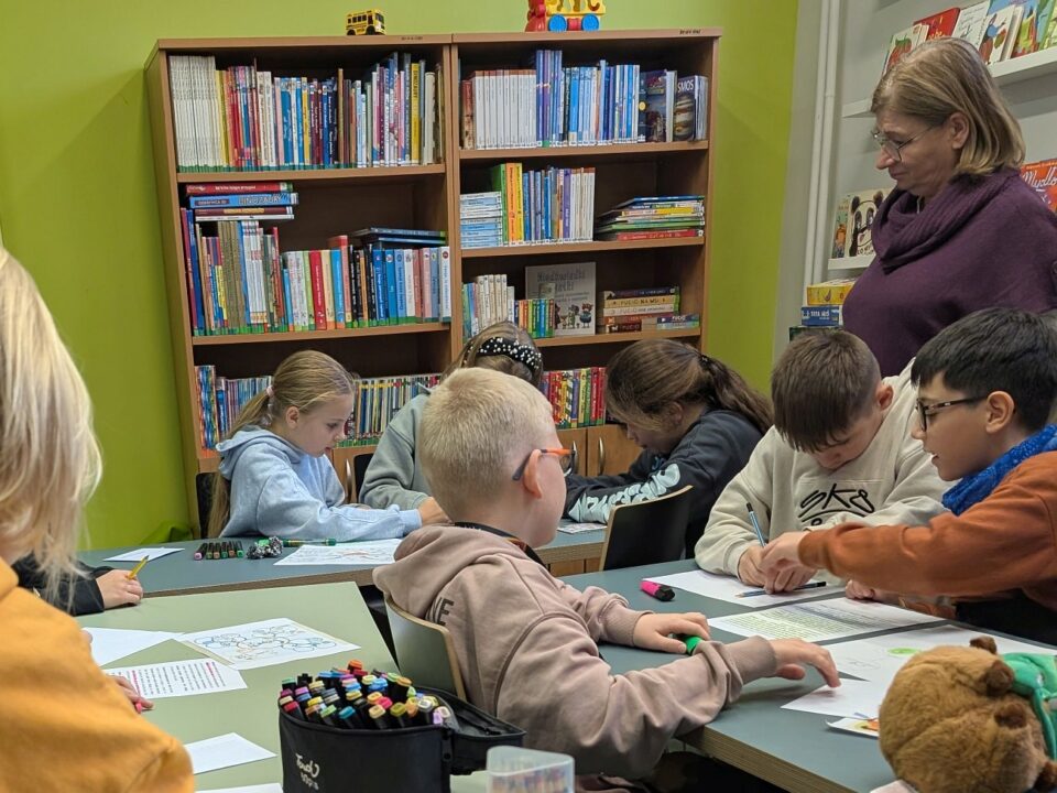 Dzieci rozwiązują zadania pod okiem nauczycielki