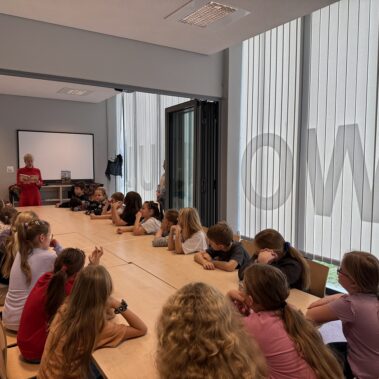 Bibliotekarka czyta na głos książkę, dzieci słuchają