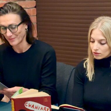 Klaudia Cygoń-Majchrowska i Aleksandra Maj siedzą przy stole, i czytają na głos