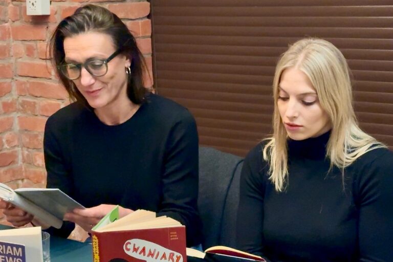 Klaudia Cygoń-Majchrowska i Aleksandra Maj siedzą przy stole, i czytają na głos