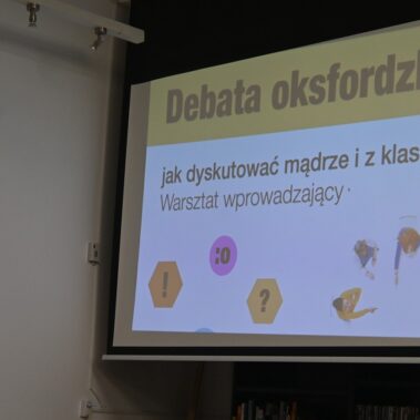 Na ekranie jest wyświetlany slajd o debacie oksfordzkiej