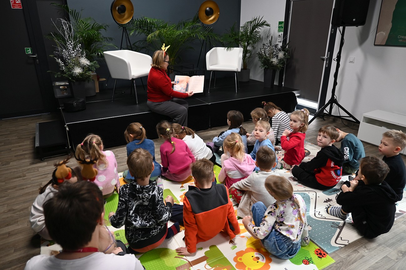 Druga bibliotekarka czyta książkę na głos, dzieci słuchają, inne ujęcie.
