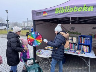 Nasze stoisko jest pod namiotem. Matka z córką biorą udział przy kole fortuny.