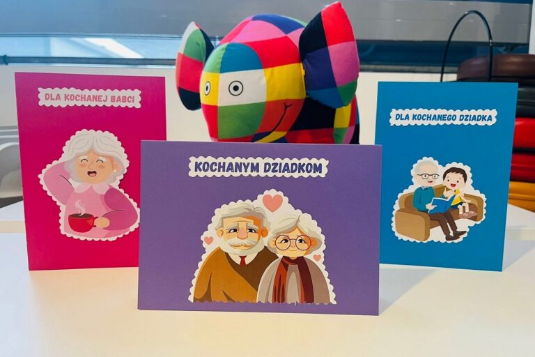 Na stole są trzy kartki w towarzystwie pluszowego kolorowego słonia