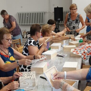 Panie przy pracy plastycznej, na stole leżą różne materiały i pudełka