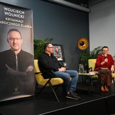 Na scenie siedzą Wojciech Wolnicki i prowadząca spotkanie