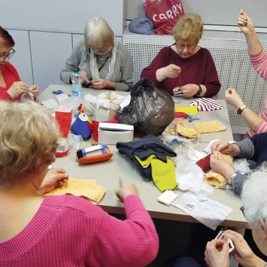 Seniorki przy pracy plastycznej, na stole leżą różne materiały