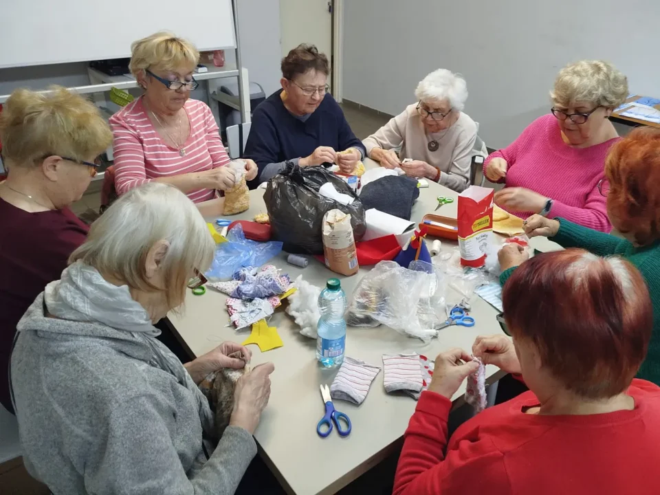 Seniorki przy pracy plastycznej, na stole leżą różne materiały, inne ujęcie