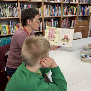 Bibliotekarka czyta na głos książkę, chłopiec słucha