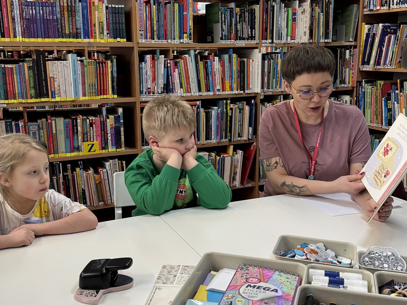 Bibliotekarka czyta na głos książkę, dzieci słuchają