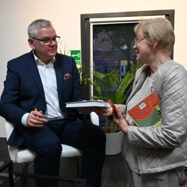 Artur Andrus przekazuje podpisaną książkę pani.