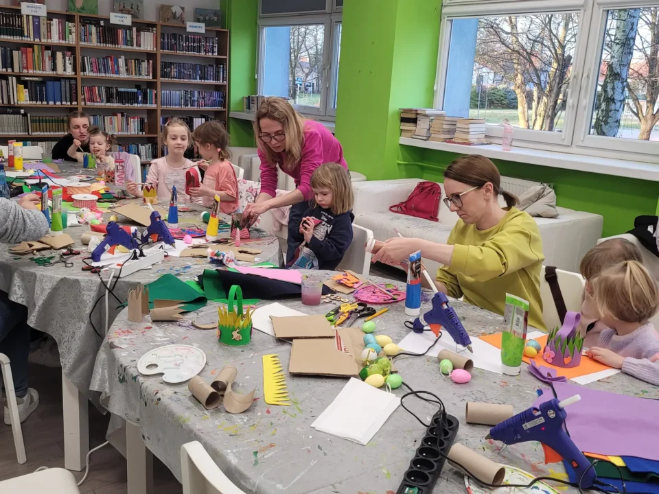 Widok ogólny na salę rodzice z dziećmi przy pracy plastycznej.