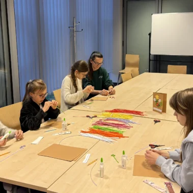 Uczestniczki przy stole i zaczynają zajęcia, na stole leżą różne materiały